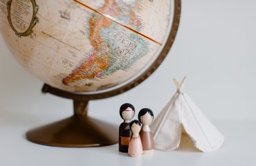 retro globe with handmade toys against gray background in room