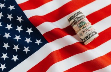american flag with rolled dollar bills